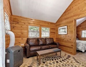 A log cabin interior with a leather sofa, a bench, and a heater.