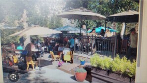 An outdoor seating area with tables and chairs, umbrellas, and potted plants.