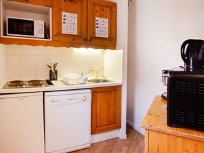 A compact kitchen with a microwave, stove, dishwasher, and a coffee maker on the counter. - Apartment pets welcome - 6 guests, mountain view (Villarodin-Bourget)