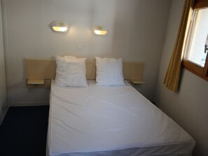 A single bed with white bedding, two wall-mounted night lights, and a window with curtains. - Apartment pets welcome - 6 guests, mountain view (Villarodin-Bourget)