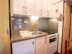 A compact kitchen with white cabinets, a stainless steel sink, a built-in oven, and a small countertop. - Well-located apartment - 4 guests (Villarodin-Bourget)