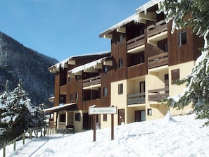 A multi-story building with balconies, a sign indicating 'Les Campanules,' and a snowy landscape with trees. - Well-located apartment - 4 guests (Villarodin-Bourget)