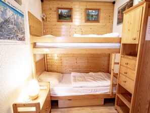 A bunk bed room with wooden walls, a desk, and a cabinet. - Apartment pets welcome, mountain view - 6 guests (Villarodin-Bourget)