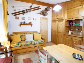 A cozy room with a wooden sofa, a wooden table, and a shelf with books and a teapot. - Apartment pets welcome, mountain view - 6 guests (Villarodin-Bourget)