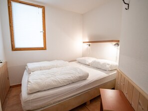 A single bed with a wooden headboard, a bedside table, and a window with blinds. - Quiet duplex chalet, stunning views - 6 guests (Villarodin-Bourget)
