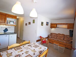 A compact living space with a dining area, kitchenette, and seating area. - Charming apartment at the foot of the slopes - 4 guests (Villarodin-Bourget)