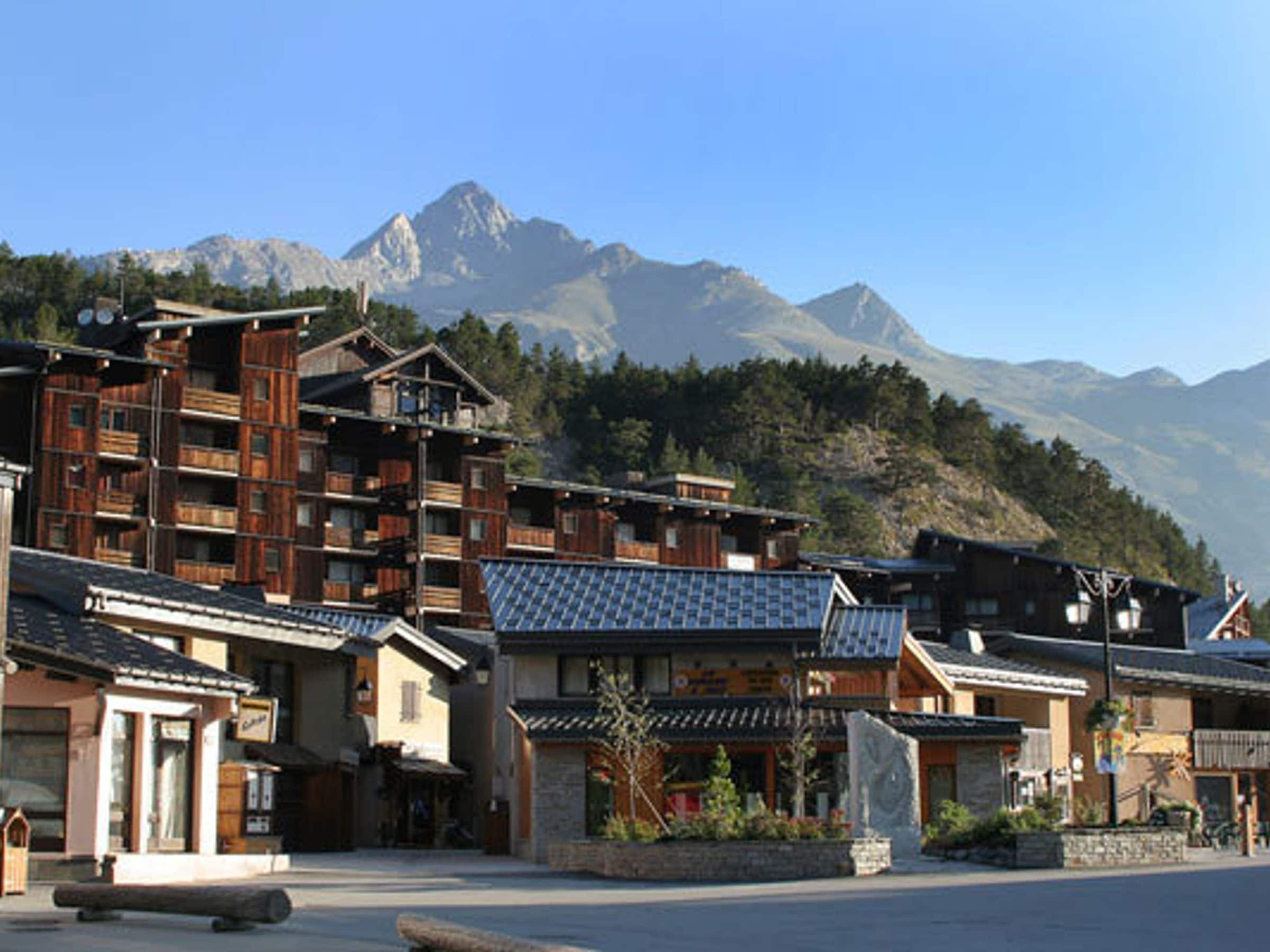 A traditional wooden building with multiple balconies, set against a backdrop of mountains.