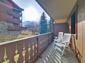 Ein Balkon mit zwei weißen Stühlen, Blick auf einen Berg und ein Gebäude mit einer Steinaußenfassade.
