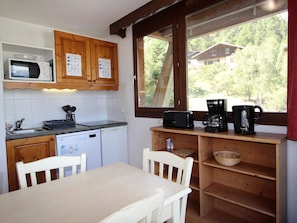 A kitchen with wooden cabinets, a microwave, a toaster, and a coffee maker. - Apartment with mountain view - 6 guests (Villarodin-Bourget)