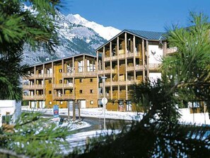 Un immeuble à plusieurs étages doté de balcons, avec une chaîne de montagnes en arrière-plan et un ciel dégagé.