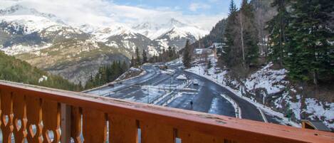 A mountainous landscape with a road and a wooden railing in the foreground.