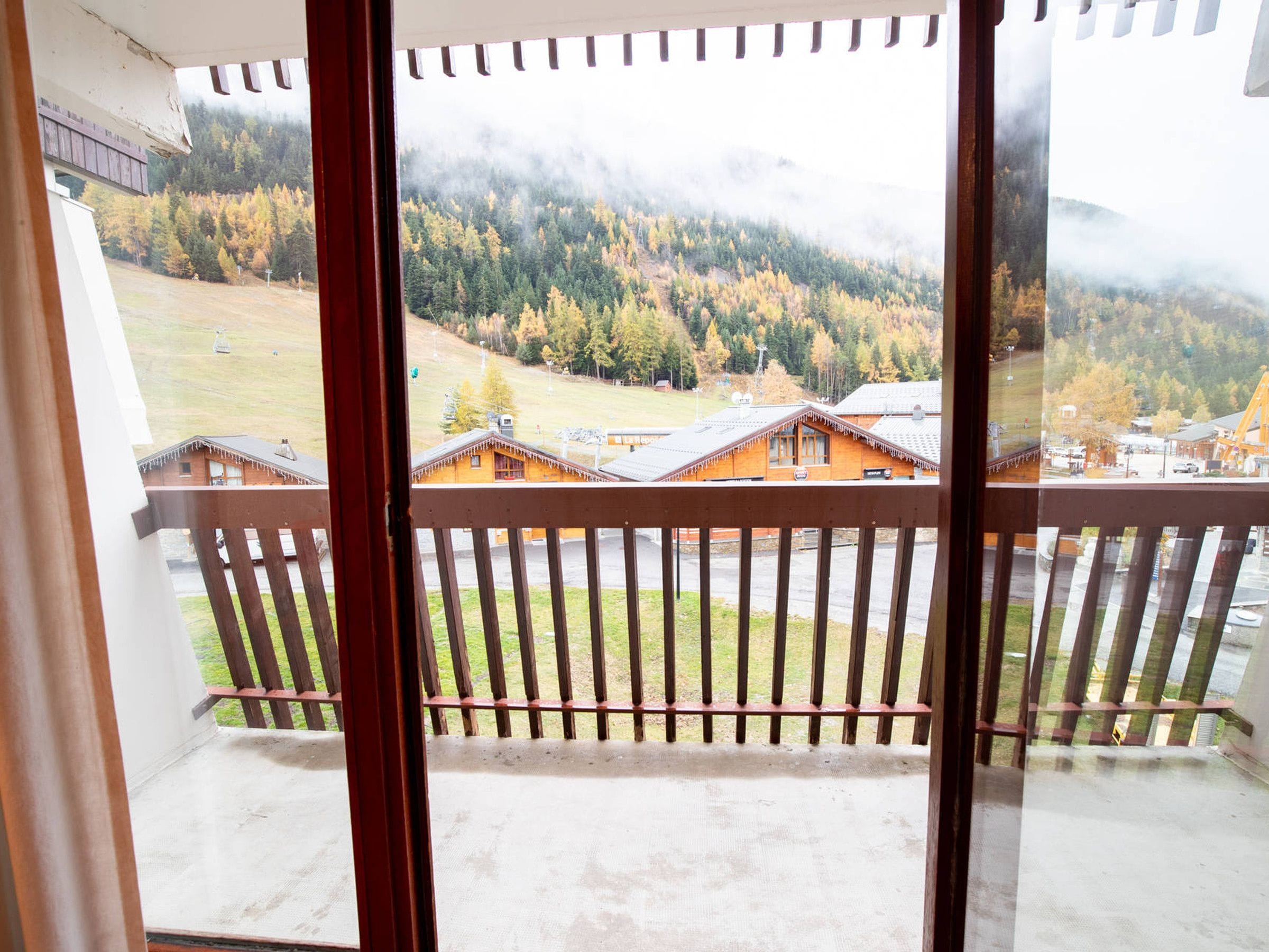 Un balcon offrant une vue sur un paysage montagneux et des chalets en bois.