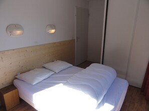 Ein Einzelbett mit weißer Bettwäsche in einem Zimmer, das ein Holz-Kopfteil und zwei Wandlampen hat.