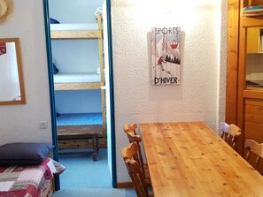 Ein Zimmer mit Etagenbetten, einem Holztisch und einem Poster an der Wand.