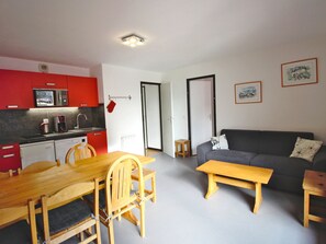 A compact living space with a kitchen, dining area, and a sofa. - Spacious apartment, mountain view - 10 guests (Valfréjus)