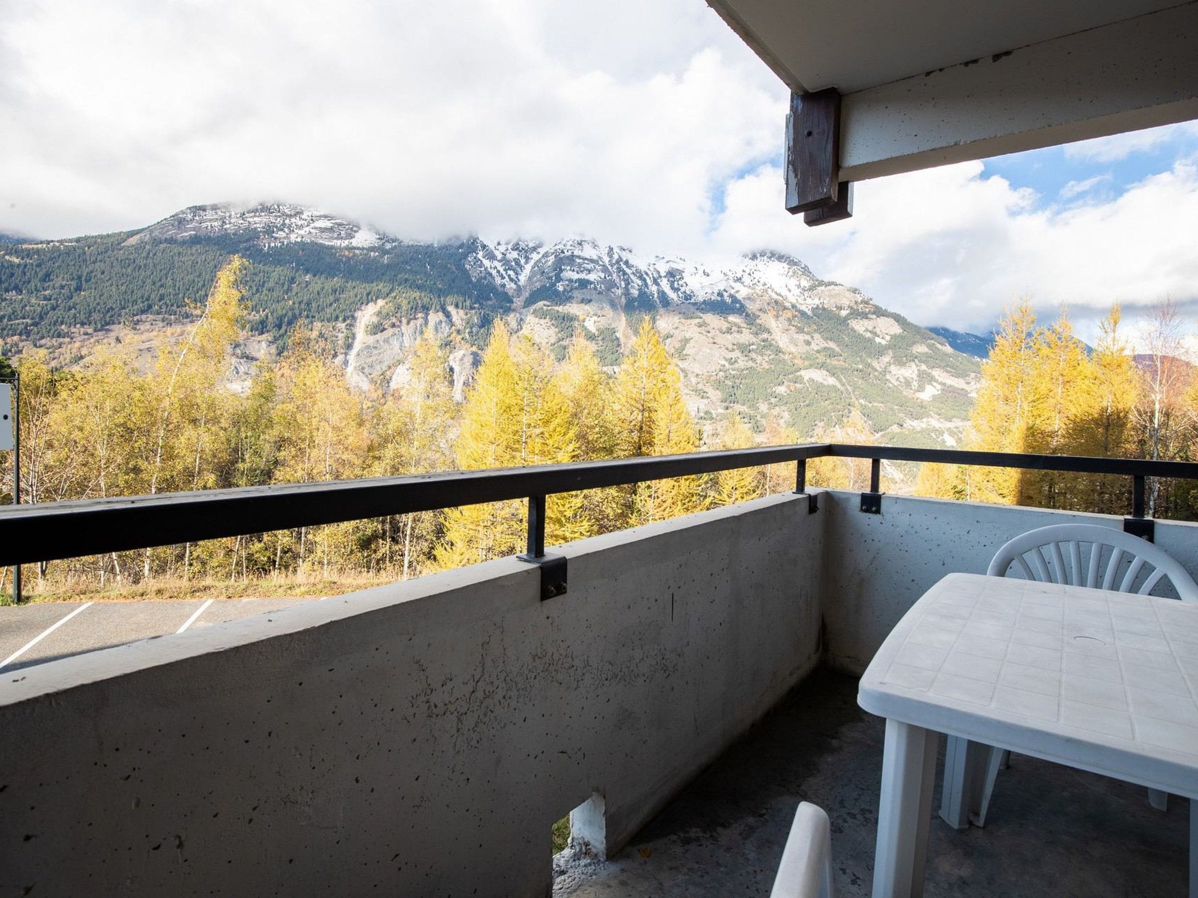 Un balcon avec un sol en béton, une table blanche et une chaise blanche.