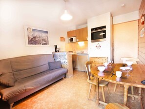 A compact living space with a sofa, dining table, chairs, a kitchen area with a microwave, oven, and cabinets. - Studio, pets allowed - Park view 4 guests (Villarodin-Bourget)