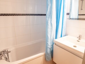 A bathroom with a bathtub, a sink, and a shower curtain. - Mountain-style apartment - 4 guests (Villarodin-Bourget)
