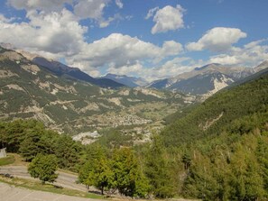 Eine gebirgige Landschaft mit einem Tal, einer Straße und einer kleinen Siedlung.