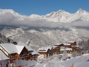 A snow-covered mountain resort with wooden buildings and a ski slope. - Charming apartment at the foot of the slopes - 6 guests (Valfréjus)