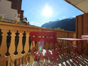A balcony with a red chair and a table, overlooking a mountainous landscape. - Lovely apartment - 6 guests, near ski lift (Valfréjus)