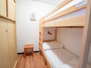 Een slaapkamer met een stapelbed, een houten bureau en een stopcontact.