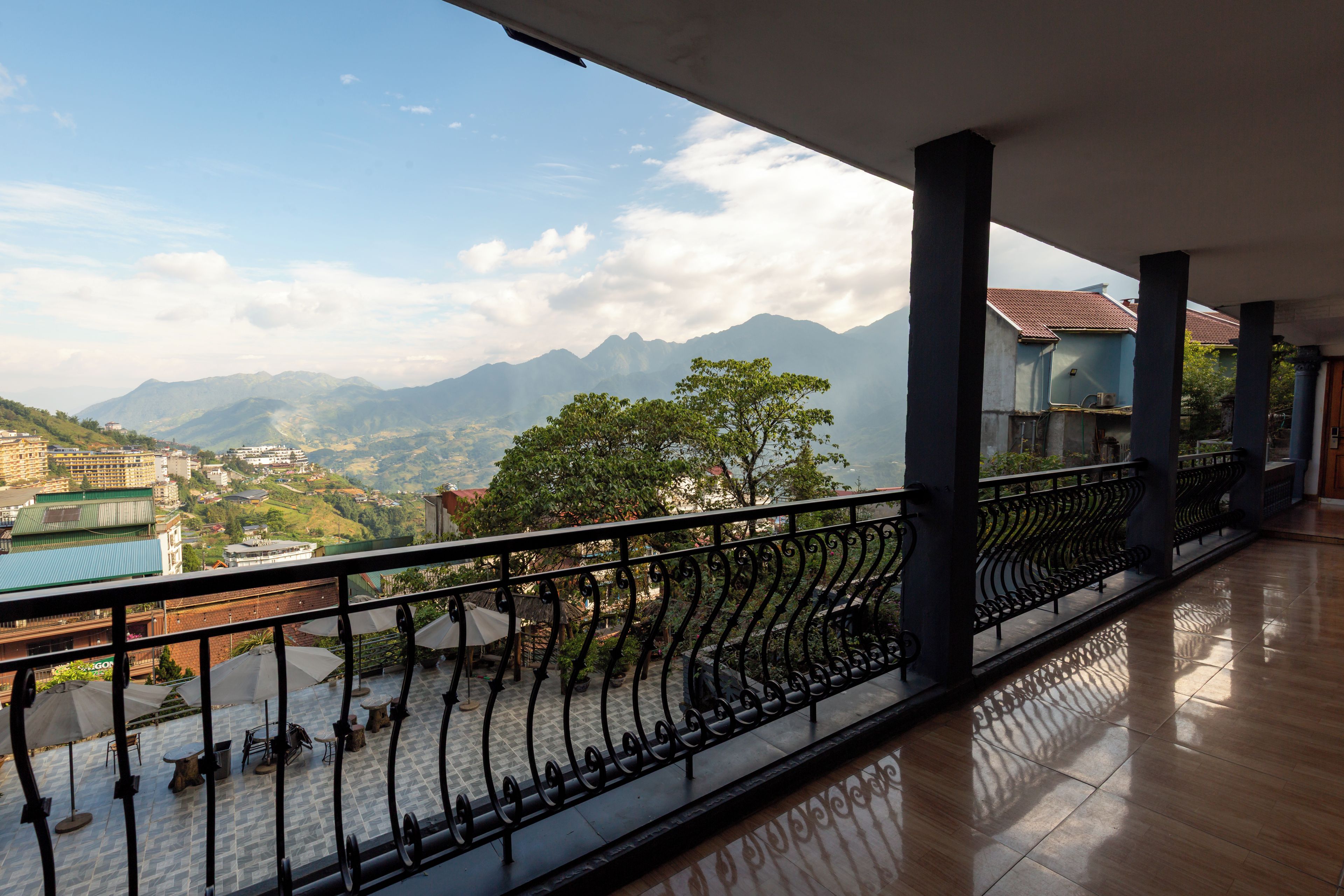 A balcony with a metal railing overlooking a mountainous landscape with buildings in the distance.