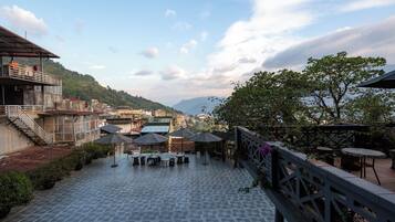 Una terraza con asientos al aire libre, vista a un paisaje urbano y una montaña en la distancia.