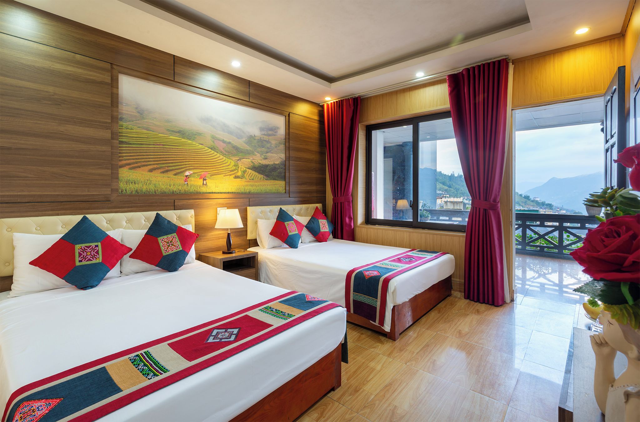 Quarto de hotel com duas camas, uma janela ampla e uma vista, e um quadro na parede.
