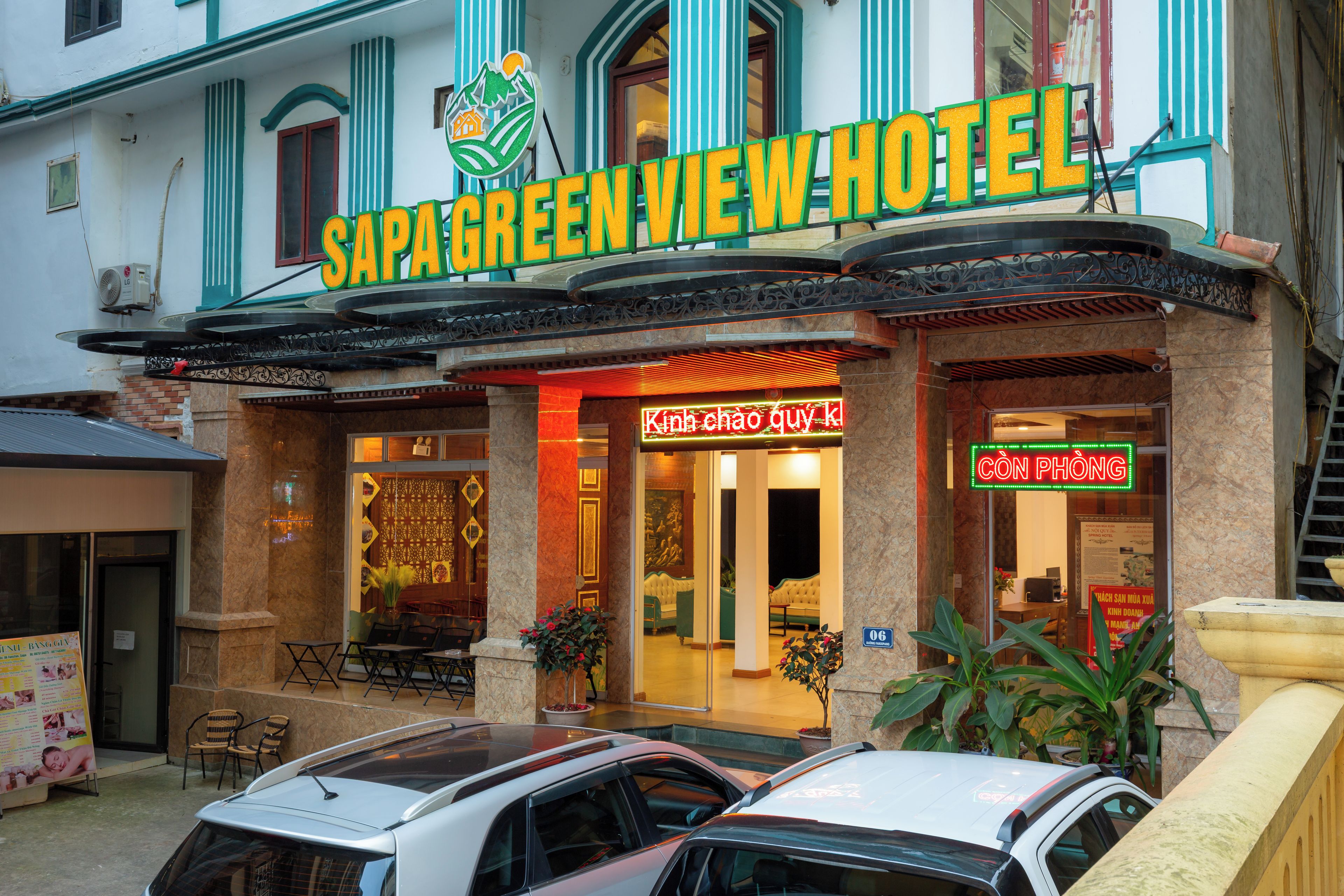 The exterior of Sapa Green View Hotel with a signboard, entrance, and two cars parked in front.