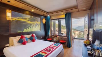 Habitación de hotel con una cama grande, un cuadro, un balcón con vistas y un televisor.
