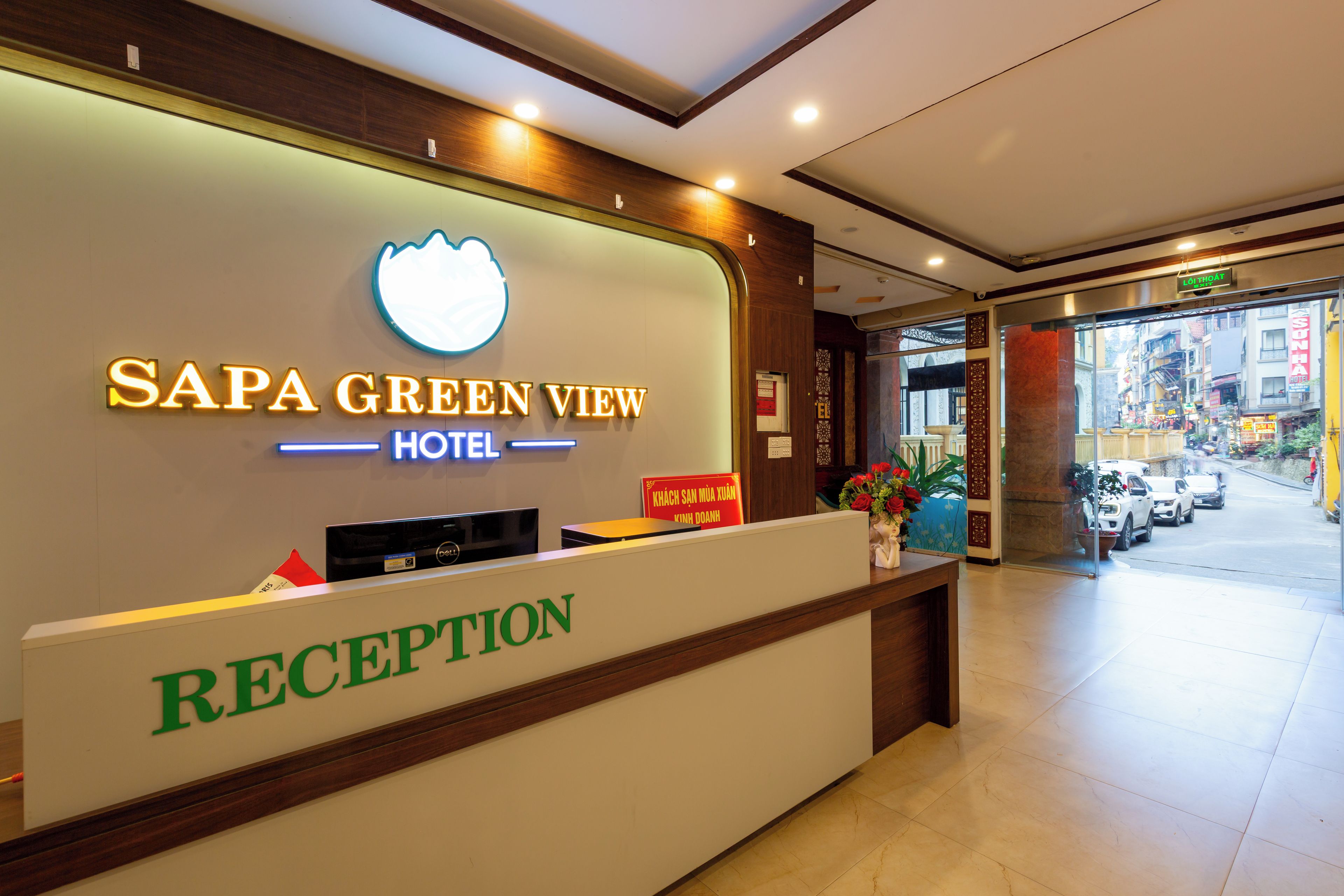 A hotel reception area with a sign for 'SAPA GREEN VIEW HOTEL' and a reception desk.