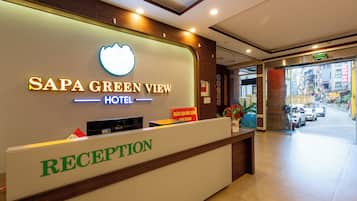 A hotel reception area with a sign for 'SAPA GREEN VIEW HOTEL' and a reception desk.