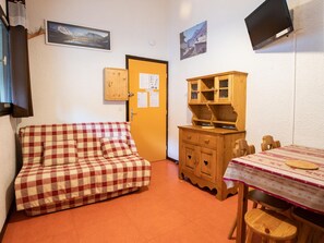 Une pièce avec un canapé à carreaux, un meuble en bois et une table entourée de chaises.
