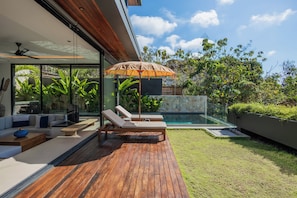 Ein moderner Außenbereich mit Pool, Holzterrasse und Liegestühlen.