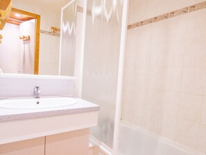 Ein Badezimmer mit einem weißen Waschbecken, einem Spiegel und einer Duschkabine.