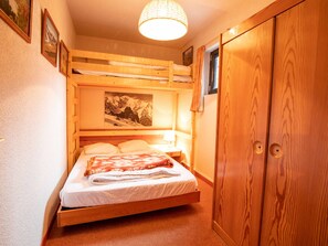 Ein Etagenbett mit Holz Kopfteil, ein Nachttisch mit Lampe und ein Kleiderschrank mit Spiegel.