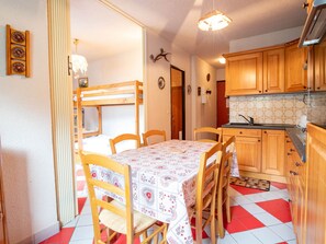 Una cucina compatta con mobili in legno, un tavolo da pranzo con sedie e un letto a castello.