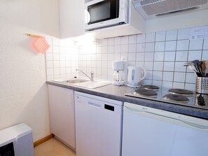 Cozinha compacta com micro-ondas, cafeteira e máquina de lavar louça.