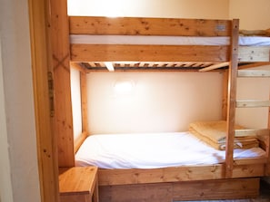 Ein Stockbett mit Holzrahmen, einer weißen Matratze und einem kleinen Nachttisch.