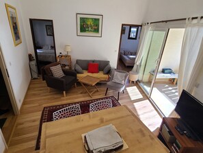 Ein Wohnzimmer mit einer Couch, Sesseln, einem Couchtisch und einem Fernseher.