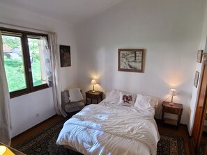 Een slaapkamer met een bed, twee nachtkastjes, een raam en een deur.