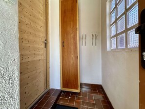 A hallway with a wooden door, a tiled floor, and a window with a grid pattern. - Cozy apartment with wifi - 4 guests (La Salle-les-Alpes)