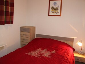 Ein Schlafzimmer mit einem Bett, einem Nachttisch, einer Lampe, einer Kommode und einem gerahmten Bild an der Wand.
