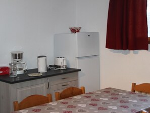 Eine kleine Küche mit Kühlschrank, Kaffeemaschine, Toaster und Spüle.