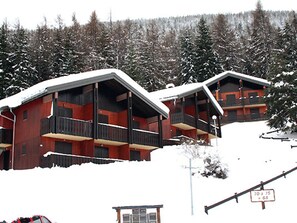 A row of wooden cabins with balconies, surrounded by snow-covered trees. - Calm apartment at the forest edge - 6 guests (Villarodin-Bourget)