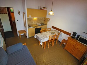 Eine kompakte Küche mit Essecke, einer Couch und einer Mikrowelle.