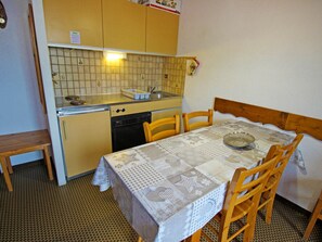 A compact kitchen with a dining table and chairs, a sink, and a dishwasher. - Calm apartment at the forest edge - 6 guests (Villarodin-Bourget)