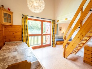 A room with a bed, a wooden dresser, a staircase, and a view through a glass door. - Spacious apartment at the foot of the slopes - 8 guests (Villarodin-Bourget)