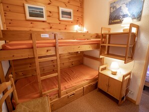 A bunk bed room with a desk and chair, a lamp, and framed pictures on the wall. - Apartment with balcony, mountain view - 6 guests (Villarodin-Bourget)